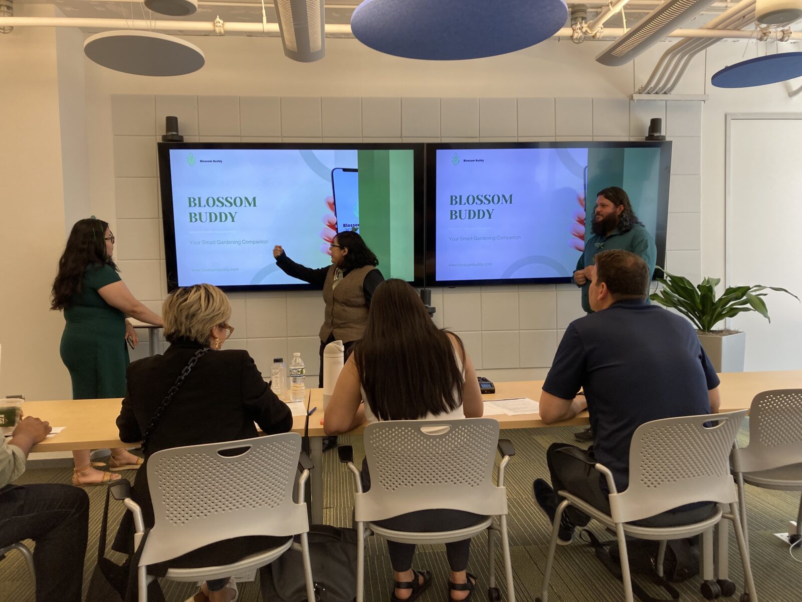 Emily Valdez presents Blossom Buddy as team members Dafne Hernandez and Jared Bears look on.