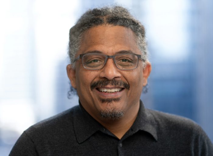 headshot of a man wearing a black polo smiling